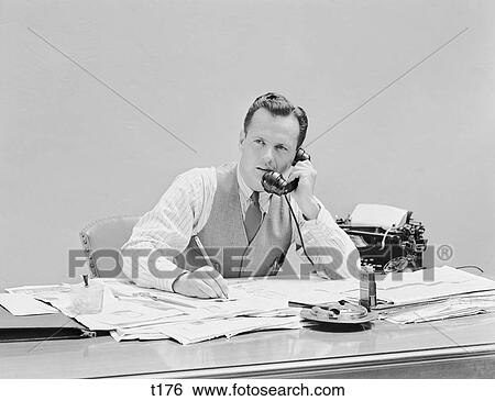 1930S 1940S Young Businessman Sitting At Desk Talking On Telephone Typewriter Wearing Vest Holding Pencil Shirtsleeves View Large Photo Image Stock Photograph - 1930S 1940S Young Businessman Sitting At Desk Talking On Telephone Typewriter Wearing Vest Holding Pencil Shirtsleeves . Fotosearch