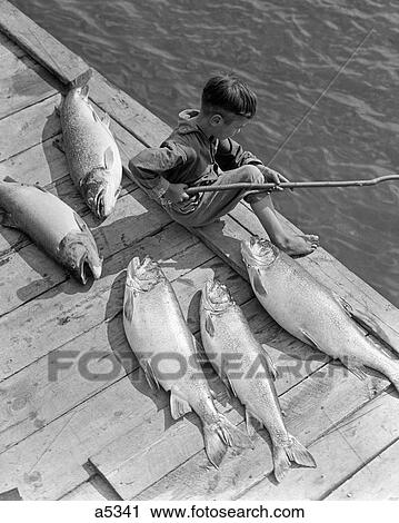 1930S Boy Seated On Dock With 5 Large Fish Fishing With Stick Pole View Large Photo Image Stock Image - 1930S Boy Seated On Dock With 5 Large Fish Fishing With Stick Pole. Fotosearch