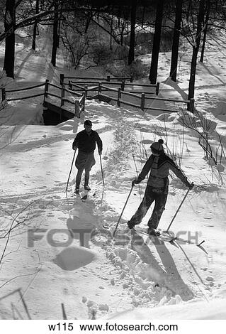 Stock Photography - 1930S Couple Man And Woman Skiing Cross Country In Woodland Snow Winter Outdoor. Fotosearch