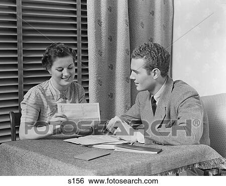 1930S Couple Man Woman Sitting At Table Going Over Papers View Large Photo Image Stock Photograph - 1930S Couple Man Woman Sitting At Table Going Over Papers . Fotosearch