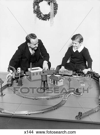 Picture - 1930S Father And Son Playing With Christmas Toy Train Set. Fotosearch