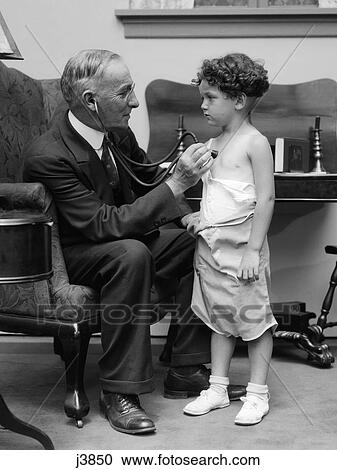 Stock Image - 1930S Man Doctor Making House Call Holding Stethoscope To Chest Of Little Boy Patient. Fotosearch