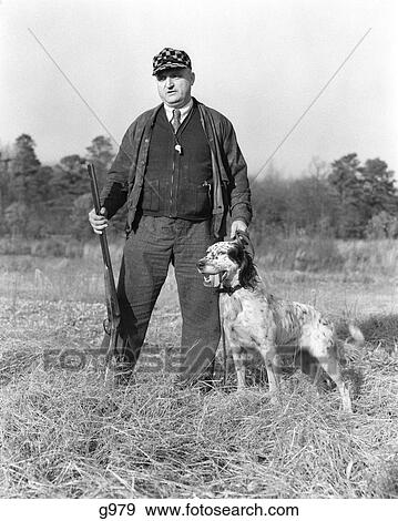 1930S Man Standing In Field Holding Shotgun And Leash Of Gordon Setter Dog View Large Photo Image Stock Photo - 1930S Man Standing In Field Holding Shotgun And Leash Of Gordon Setter Dog. Fotosearch