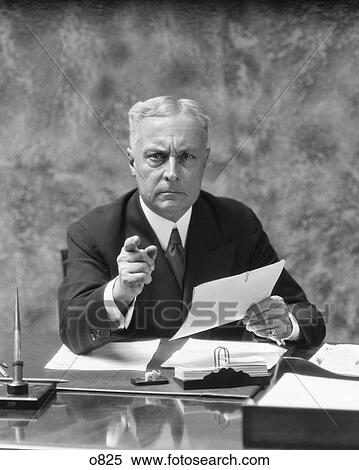 1930S Older Man Sitting At Desk In Office Pointing With Stern Expression View Large Photo Image Stock Photography - 1930S Older Man Sitting At Desk In Office Pointing With Stern Expression. Fotosearch