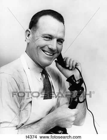 1930S Smiling Grocer In Apron On Candlestick Phone View Large Photo Image Picture - 1930S Smiling Grocer In Apron On Candlestick Phone. Fotosearch