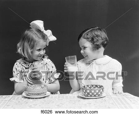 1930S Two Smiling Little Girls Drinking Milk Bowl Of Cereal Talking Laughing Eating View Large Photo Image Stock Photograph - 1930S Two Smiling Little Girls Drinking Milk Bowl Of Cereal Talking Laughing Eating. Fotosearch