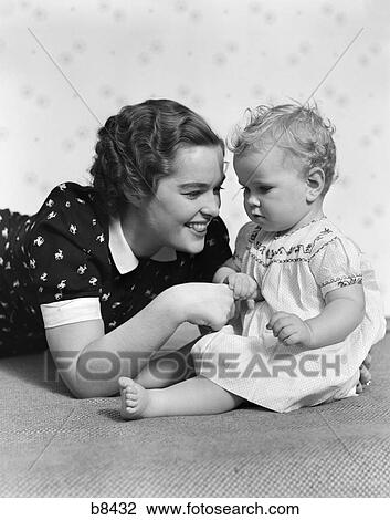 1930S Woman Mother Smiling Sitting Playing With Baby Daughter View Large Photo Image Stock Image - 1930S Woman Mother Smiling Sitting Playing With Baby Daughter. Fotosearch