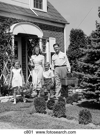 Stock Image - 1940S 1950S Family Of Four Walking Out Of House Carrying Picnic Baskets Thermos & Jug. Fotosearch