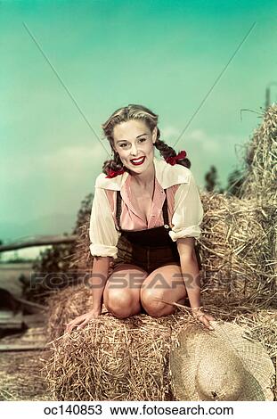 1940S 1950S Smiling Woman Hair In Braids Wearing Overalls Sitting On Hay Stack Holding Straw Hat Looking At Camera View Large Photo Image Stock Image - 1940S 1950S Smiling Woman Hair In Braids Wearing Overalls Sitting On Hay Stack Holding Straw Hat Looking At Camera. Fotosearch