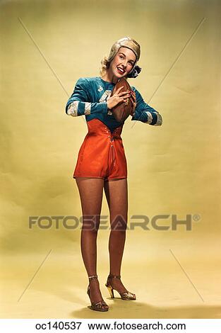 1940S 1950S Smiling Woman Pinup Wearing Football Player Uniform Costume Holding Football View Large Photo Image Stock Photo - 1940S 1950S Smiling Woman Pinup Wearing Football Player Uniform Costume Holding Football. Fotosearch