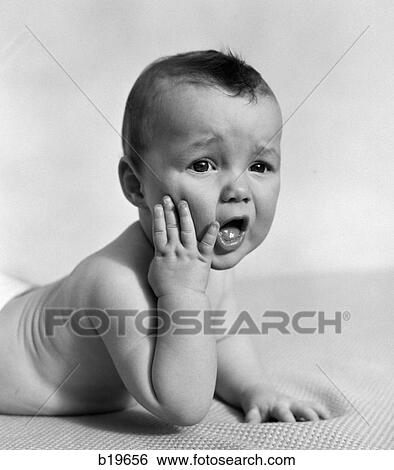 1940S Baby Lying On Stomach With Hand On Cheek & Distressed Look On Face View Large Photo Image Stock Photograph - 1940S Baby Lying On Stomach With Hand On Cheek & Distressed Look On Face. Fotosearch