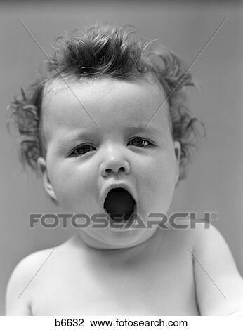 Stock Image - 1940S Baby Portrait Close-Up Yawning Sleepy Mouth Open Wide Studio Indoor. Fotosearch