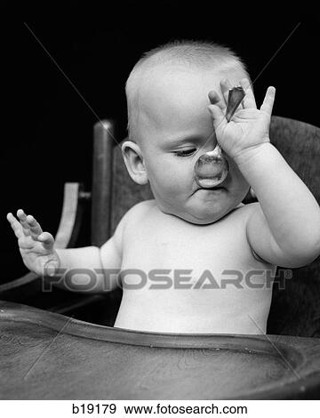 1940S Baby Sitting In High Chair With Spoon In Mouth View Large Photo Image Stock Photo - 1940S Baby Sitting In High Chair With Spoon In Mouth. Fotosearch