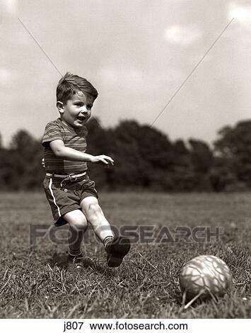 1940S Boy Kicking Ball In Grassy Field View Large Photo Image Stock Photo - 1940S Boy Kicking Ball In Grassy Field. Fotosearch