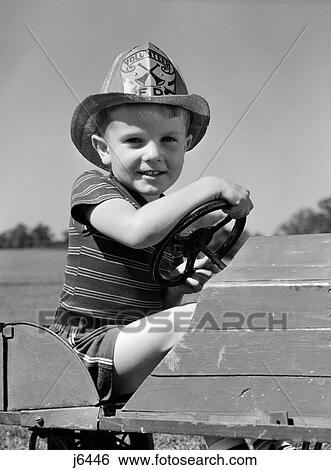 1940S Boy Playing Fireman In Toy Fire Truck Wearing Fireman'S Safety Hat Holding Steering Wheel Smiling View Large Photo Image Stock Photograph - 1940S Boy Playing Fireman In Toy Fire Truck Wearing Fireman'S Safety Hat Holding Steering Wheel Smiling. Fotosearch