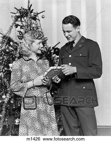 1940S Couple Man Soldier Giving Gift To Woman By Christmas Tree View Large Photo Image Stock Photograph - 1940S Couple Man Soldier Giving Gift To Woman By Christmas Tree. Fotosearch