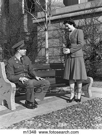 Stock Photo - 1940S Couple Woman Taking Photo Of Soldier Sitting On Bench. Fotosearch