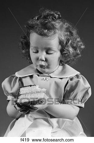 Stock Photo - 1940S Little Girl Eating Piece Of Cake With Chocolate Icing. Fotosearch