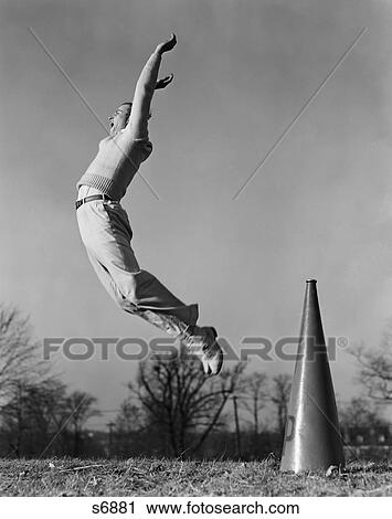 Stock Image - 1940S Male Cheerleader Jumping Cheering Megaphone On Ground. Fotosearch