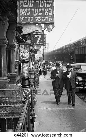 Stock Image - 1940S Manhattan Lower East Side With Signs In Yiddish On Delancy Street Barber Shop With Williamsburg Bridge In Background. Fotosearch