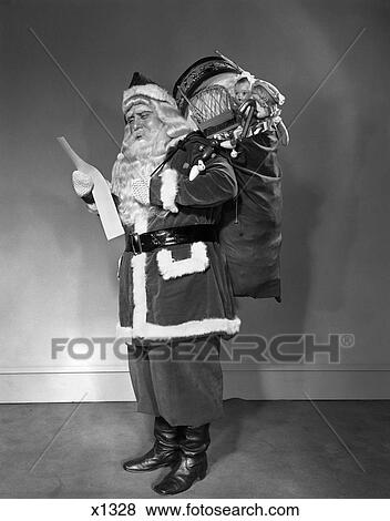 Stock Photo - 1940S Santa Claus Carrying Bag Full Of Toys Reading List. Fotosearch