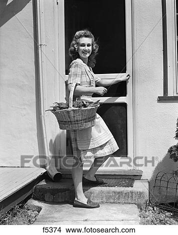 1940S Woman Wearing Plaid Dress Apron Farmhouse Screen Door Holding Basket Vegetables View Large Photo Image Picture - 1940S Woman Wearing Plaid Dress Apron Farmhouse Screen Door Holding Basket Vegetables. Fotosearch