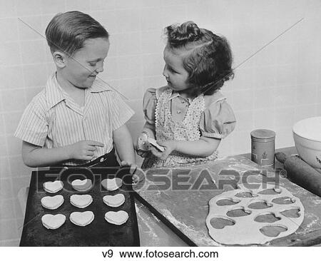 1940S Young Smiling Girl And Boy Baking Heart Shaped Valentine Cookies View Large Photo Image Stock Photo - 1940S Young Smiling Girl And Boy Baking Heart Shaped Valentine Cookies. Fotosearch