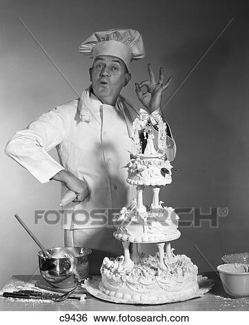 Stock Photograph - 1950S 1960S 1970S Man Portrait Baker Making Ok Success Hand Sign Next To Three Tier Wedding Cake Bride And Groom On Top. Fotosearch