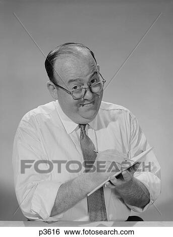 Stock Photograph - 1950S 1960S Balding Businessman Wearing Eyeglasses Shirt Sleeves Smiling Writing Notepad Looking At Camera. Fotosearch