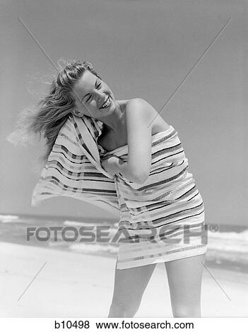 Stock Photo - 1950S 1960S Blond Woman Wrapped In Stripped Towel Drying Hair On Beach Smiling. Fotosearch
