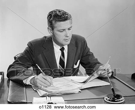 Stock Photo - 1950S 1960S Businessman At Desk Looking Over Files Papers Making Notes With Pencil. Fotosearch