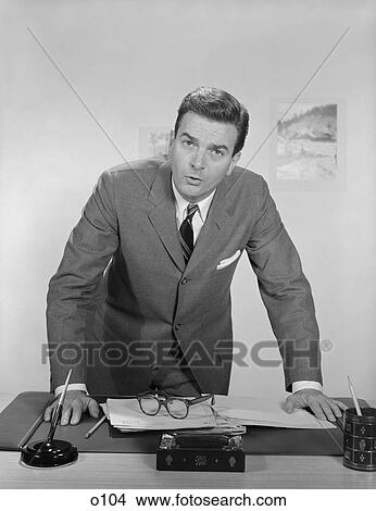 1950S 1960S Businessman Leaning Over Desk Serious Expression Looking Forward View Large Photo Image Picture - 1950S 1960S Businessman Leaning Over Desk Serious Expression Looking Forward. Fotosearch
