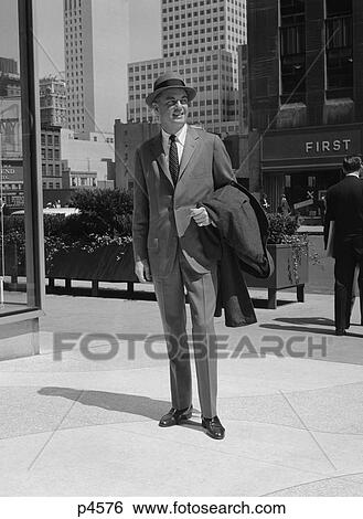 1950S 1960S Businessman Wearing Suit Hat Carrying Top Coat Standing On City Street View Large Photo Image Stock Photograph - 1950S 1960S Businessman Wearing Suit Hat Carrying Top Coat Standing On City Street . Fotosearch