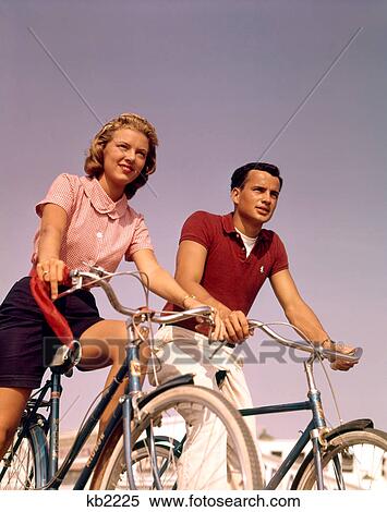 Stock Photography - 1950S 1960S Couple Man Woman Riding Bicycles Outdoors. Fotosearch