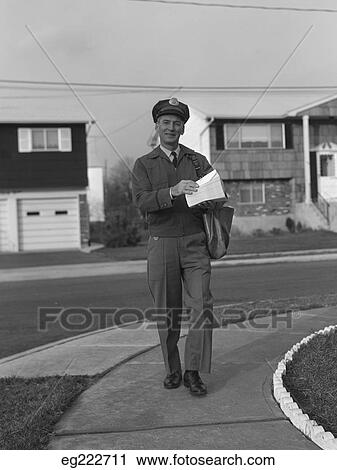 Stock Image - 1950S 1960S Mailman Walking Outside Carrying Mail. Fotosearch