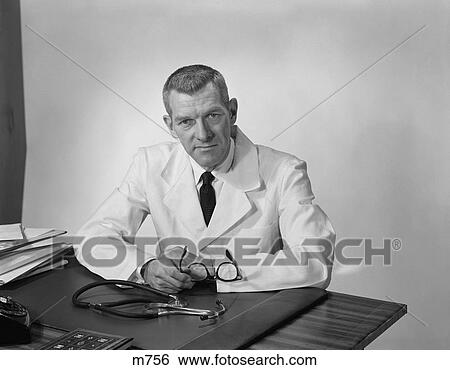 1950S 1960S Portrait Male Doctor Sitting At Desk Serious Expression View Large Photo Image Stock Photograph - 1950S 1960S Portrait Male Doctor Sitting At Desk Serious Expression. Fotosearch