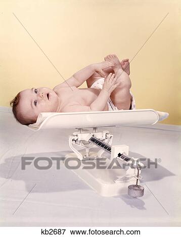 Stock Photo - 1950S 1960S Smiling Baby Lying On Weight Scale. Fotosearch