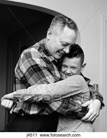 Stock Image - 1950S 1960S Smiling Father And Son Hugging Indoor. Fotosearch