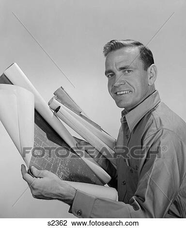 Stock Image - 1950S 1960S Smiling Man Builder Contractor Holding Blueprints Looking At Camera. Fotosearch