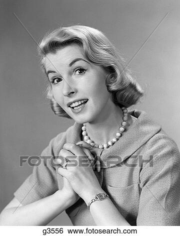Stock Photograph - 1950S 1960S Smiling Woman Hands Clasped To Chest Wearing Beads Necklace. Fotosearch