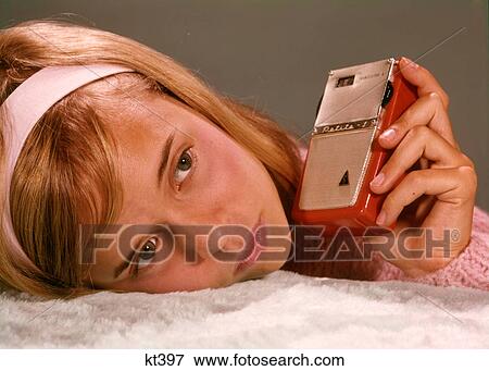 1950S 1960S Teenage Girl Holding Red Silver Small Transistor Radio To Her Ear Listening View Large Photo Image Stock Photo - 1950S 1960S Teenage Girl Holding Red Silver Small Transistor Radio To Her Ear Listening. Fotosearch
