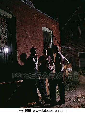 Stock Photograph - 1950S 1960S Three Teenage Boys Loitering In Alley At Night Smoking Cigarettes. Fotosearch