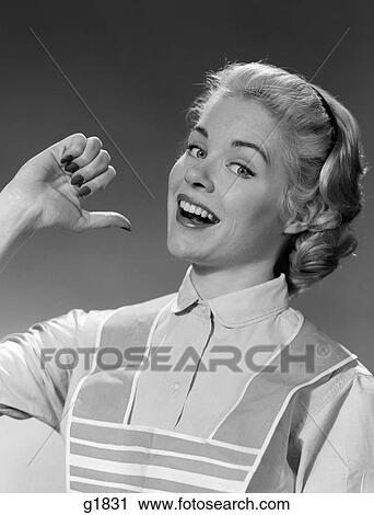 Stock Image - 1950S 1960S Woman Housewife In Apron Smiling Proudly Pointing At Herself With Thumb. Fotosearch