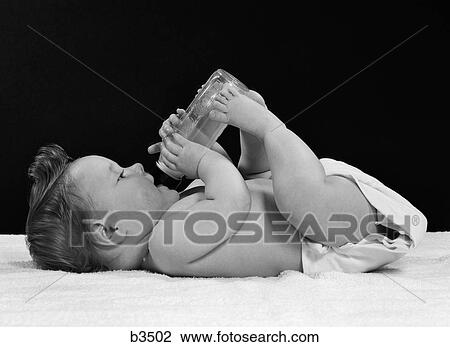 1950S Baby Lying On Back Drinking From Bottle Held By Feet & Hands View Large Photo Image Stock Image - 1950S Baby Lying On Back Drinking From Bottle Held By Feet & Hands. Fotosearch