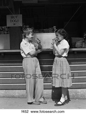 Stock Image - 1950S Boy Girl Eating Hot Dogs At Take Out Stand. Fotosearch