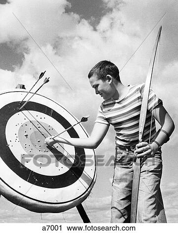 1950S Boy Jeans Striped T-Shirt Holding Bow & Pulling Arrow Out Of Target Bull'S-Eye View Large Photo Image Stock Image - 1950S Boy Jeans Striped T-Shirt Holding Bow & Pulling Arrow Out Of Target Bull'S-Eye . Fotosearch