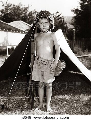 Stock Photo - 1950S Boy Playing Soldier Standing With Rifle Helmet Canteen Tent. Fotosearch