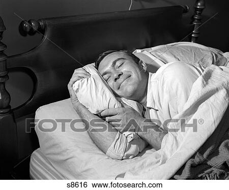 Stock Photograph - 1950S Close-Up Of Man Sleeping Peacefully In Bed Hugging Pillow Indoor. Fotosearch