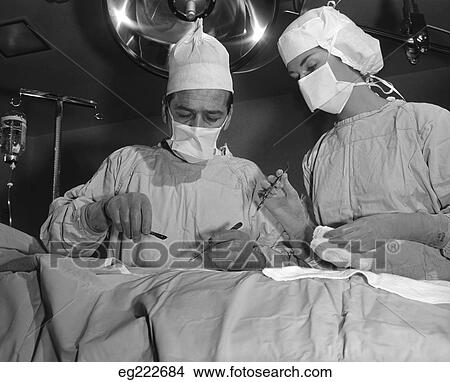 Picture - 1950S Doctor And Nurse Standing Over Patient About To Operate. Fotosearch