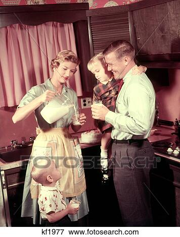 1950S Family In Kitchen Mother Pouring Milk From Pitcher For Dad And Kids View Large Photo Image Stock Photo - 1950S Family In Kitchen Mother Pouring Milk From Pitcher For Dad And Kids. Fotosearch
